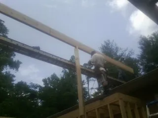 Carpenter setting a ridge beam over a new addition frame — Ice Dam Removal by Roofing Brothers in Garrison