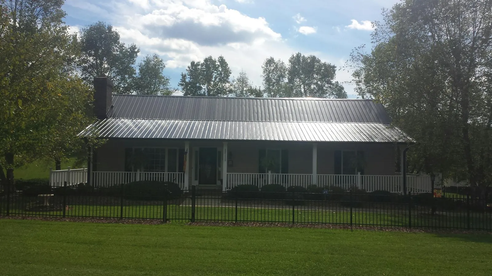 Gray metal roof on a brick ranch with a full width front porch — Gutter Guard Installation work by our crew in Garrison