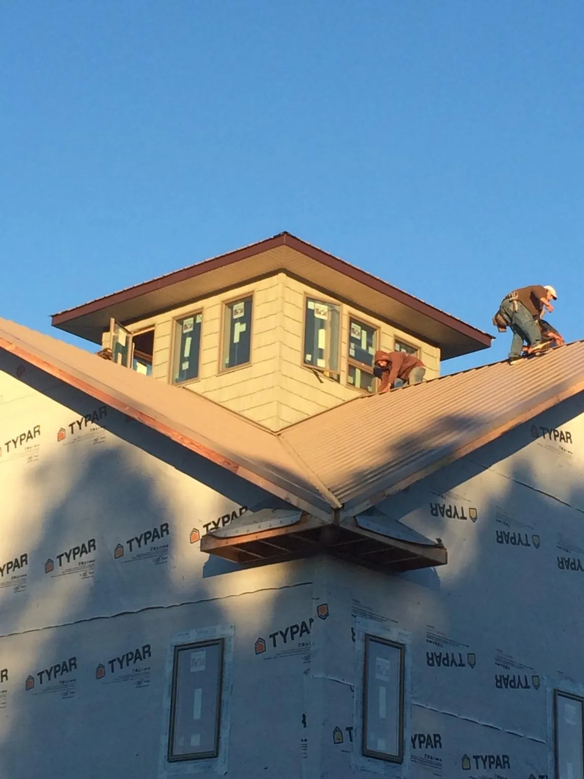 Roofers working around a rooftop cupola on a new metal roof at sunset — Roof Waterproofing in Garrison by Roofing Brothers